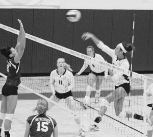 Senior Kristy Gilchrist (#20) spikes the ball over the heads and hands of the Wayne State team. Gilchrist has made over 1,000 kills over her career and has earned the title title of GLIAC North Division Player of the Week twice just this season. Photo By: Kristyn Sonnenberg | Photo Editor