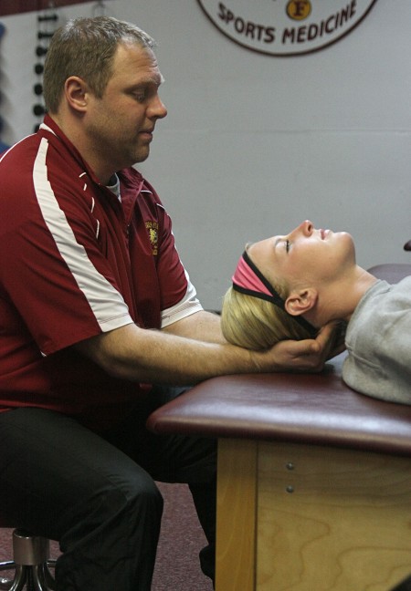 Behind the Scenes: Trainer Tim Glover helps stretch out Makenzi Peterson, a junior on the softball team. Trainers are the people behind the scenes that help Bulldog athletes stay healthy. Photo By: Michael Fleming | Web Editor