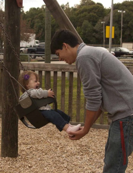Juggling Life: Ethan Pineda and daughter Alivia play on the swings at Hemlock Park. Pineda currently works several jobs while taking 16 credits and raising his daughter. Photo By: Kate Dupon | Photo Editor