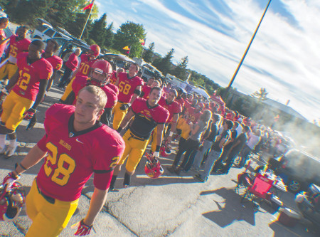 March of the Bulldogs: Defensive Back Kyle Kujawa (28) and the Bulldogs march through a crowd of eager fans during the tailgate party before their first home game of the season against Lake Erie. Photo By: Eric Trandel | Photo Editor