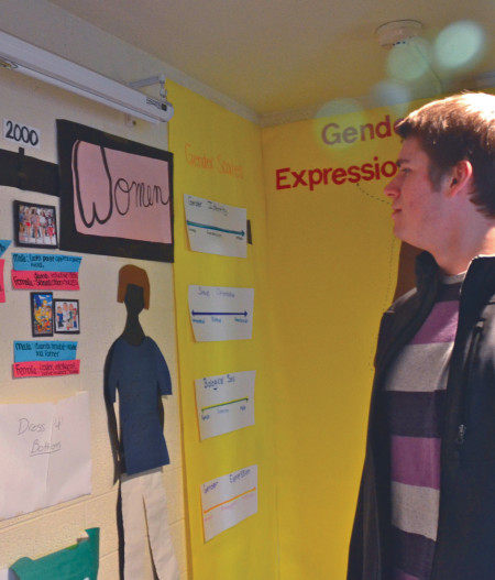 Sophomore automotive management student Alex Laduke looks over a timeline showing how men and women have been portrayed by society as part of the Gender Exhibit held in Helen Ferris Hall. Photo By: Olivia Odette | Photographer