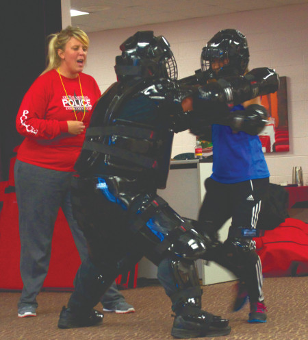 Officers Joy Paquette and James Wing instruct a female participant during the two-day Rape Aggression Defense class. Sgt. Wing and students dress in full protective gear as they practiced defense tactics.  Photo By: Melanie Ronquillo | Photographer