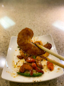 Meatless shrimp held in chop sticks over a plate of food.